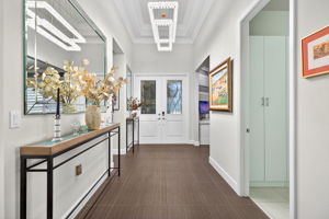 This gorgeous 12' x 24' premium plank tile is throughout the home! Etched custom glass inserts in grand double door entry, designer chandelier, and custom mirrors complete this glamorous entry.