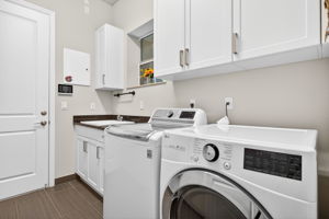 Sink, window, cabinetry galore, and updated washer and gas dryer comprise this laundry room.