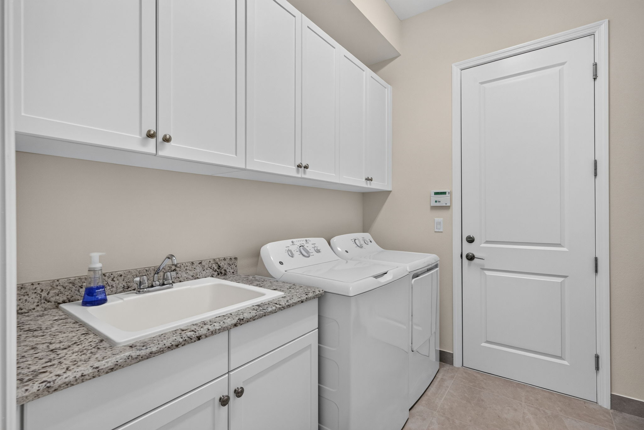 Laundry room with large utility tub, lots of cabinets for storage PLUS a whole opposite wall to make a mud room if you wish, or to install drying racks/folding table.
