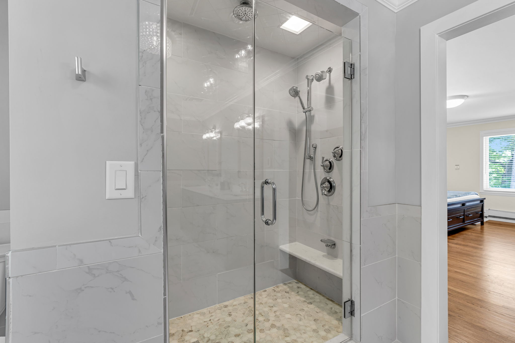 Walk-in glass enclosed tile surround shower with dual jets and bench seat