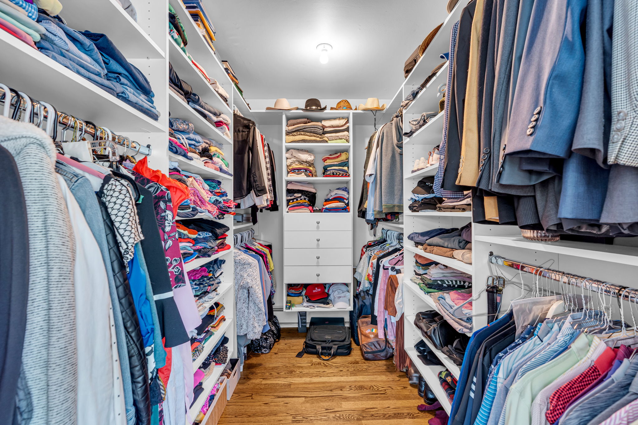 Primary walk-in closet with built-in wardrobe cabinets