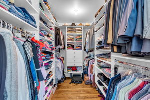 Primary walk-in closet with built-in wardrobe cabinets