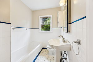 Retro main floor bathroom with bathtub and pedestal sink.