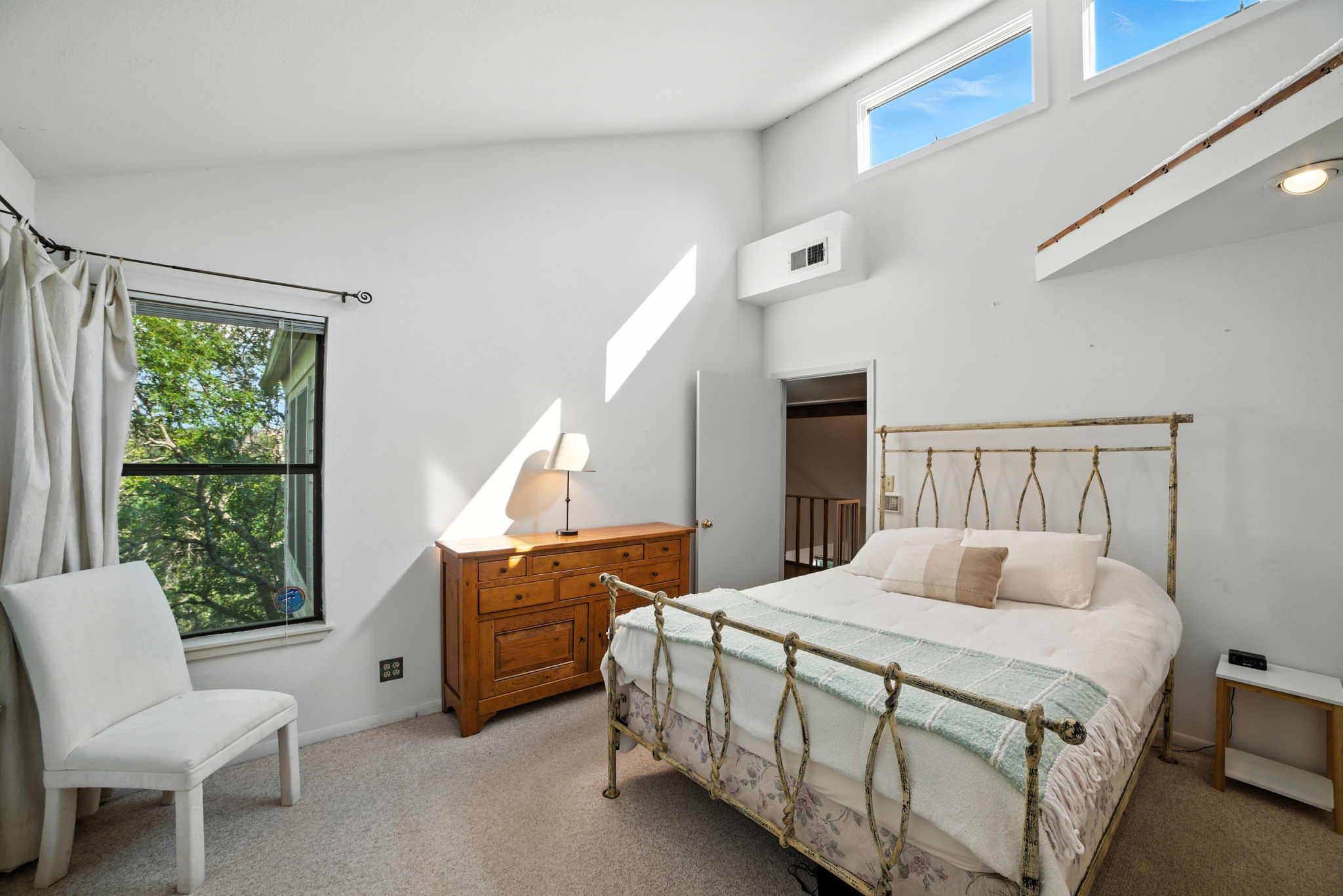 The spacious primary bedroom features high ceilings, treetop views, and access to a unique loft space ideal for a reading nook or meditation retreat. Thoughtful design adds character while still offering everyday comfort.