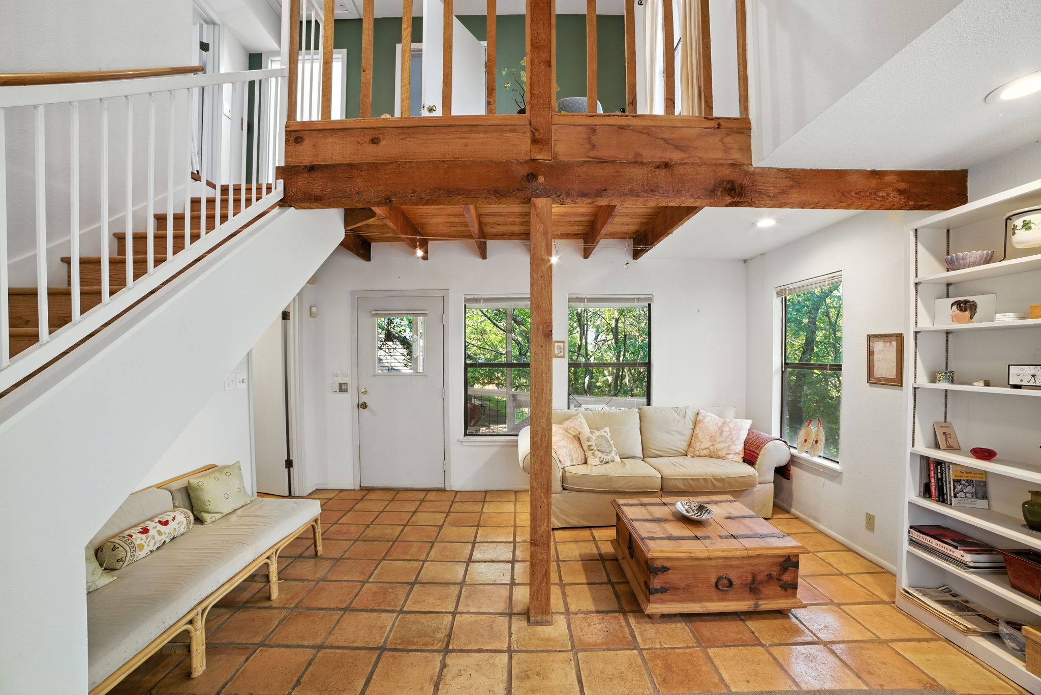 From the entryway, the home opens into a light-filled living room with rustic tile floors and warm wood accents. Large windows showcase treetop views, while the flexible layout flows naturally to the back patio and includes a conveniently located bathroom near the rear entrance—making the space ideal for both everyday living and entertaining.