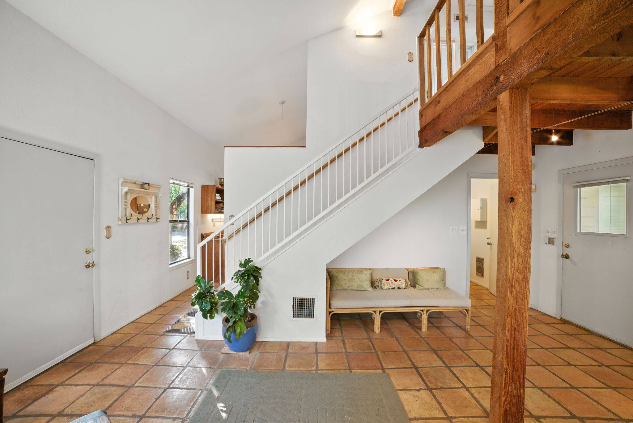 The entryway welcomes you with soaring ceilings, warm tile floors, and an open staircase that sets the tone for the home’s spacious design. Natural light and rustic wood accents highlight the inviting character, offering a true blend of comfort and Austin charm.