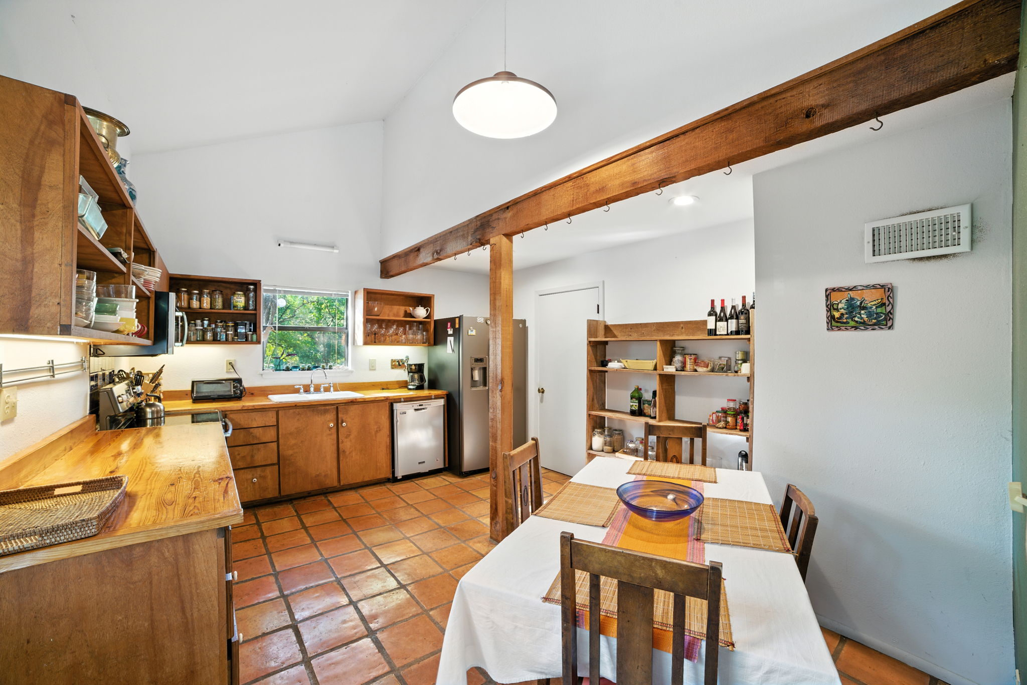 The kitchen combines warmth and functionality with wood cabinetry, tile floors, and a connected dining space that feels welcoming and relaxed. Just beyond, a spacious laundry room offers abundant storage, making it easy to double as a pantry or utility area to keep daily life organized