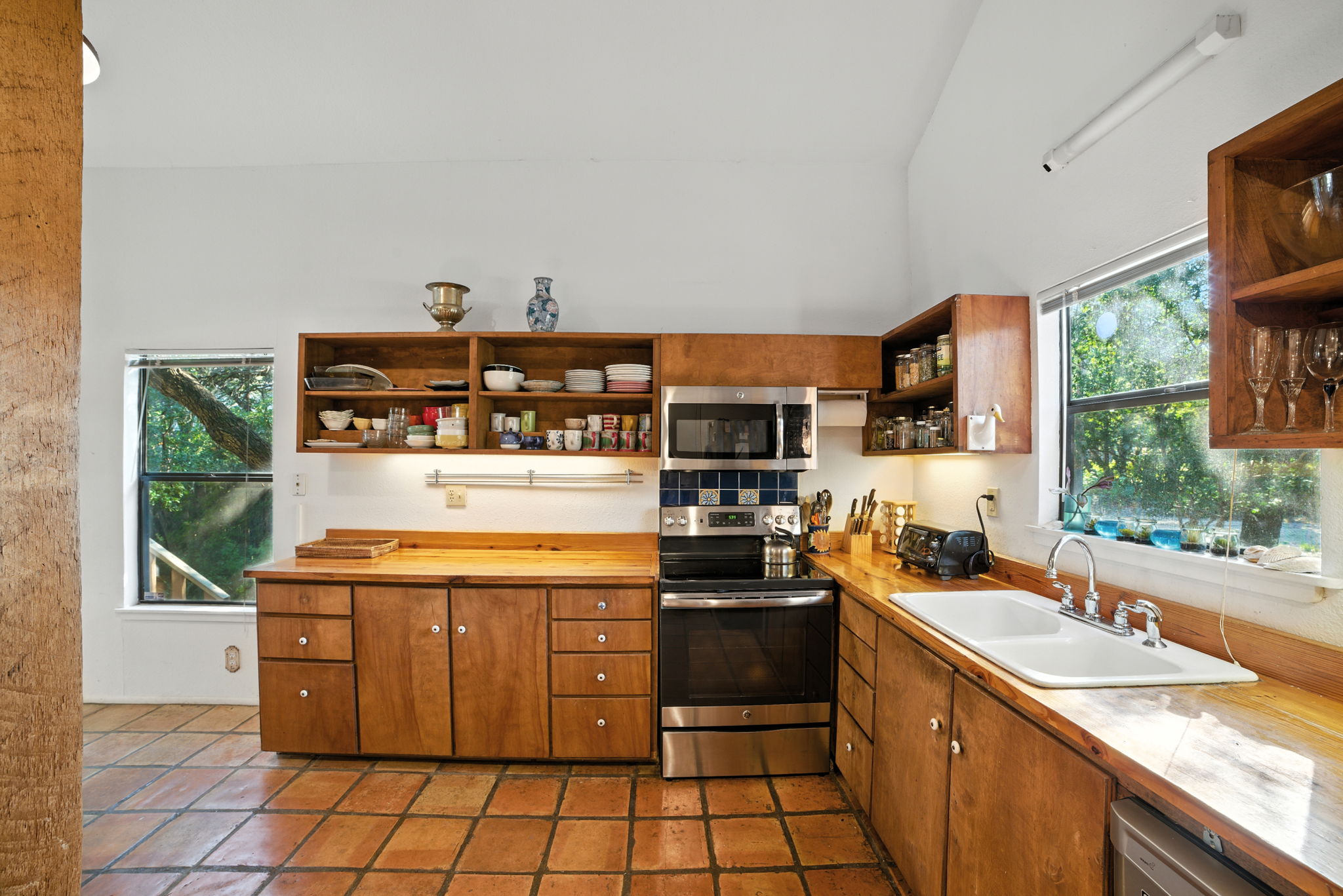 The kitchen is filled with natural light from windows that frame the surrounding greenery, creating a warm and inviting place to cook or gather. With ample counter space, updated appliances, and a functional layout, this space is designed for both everyday meals and entertaining.