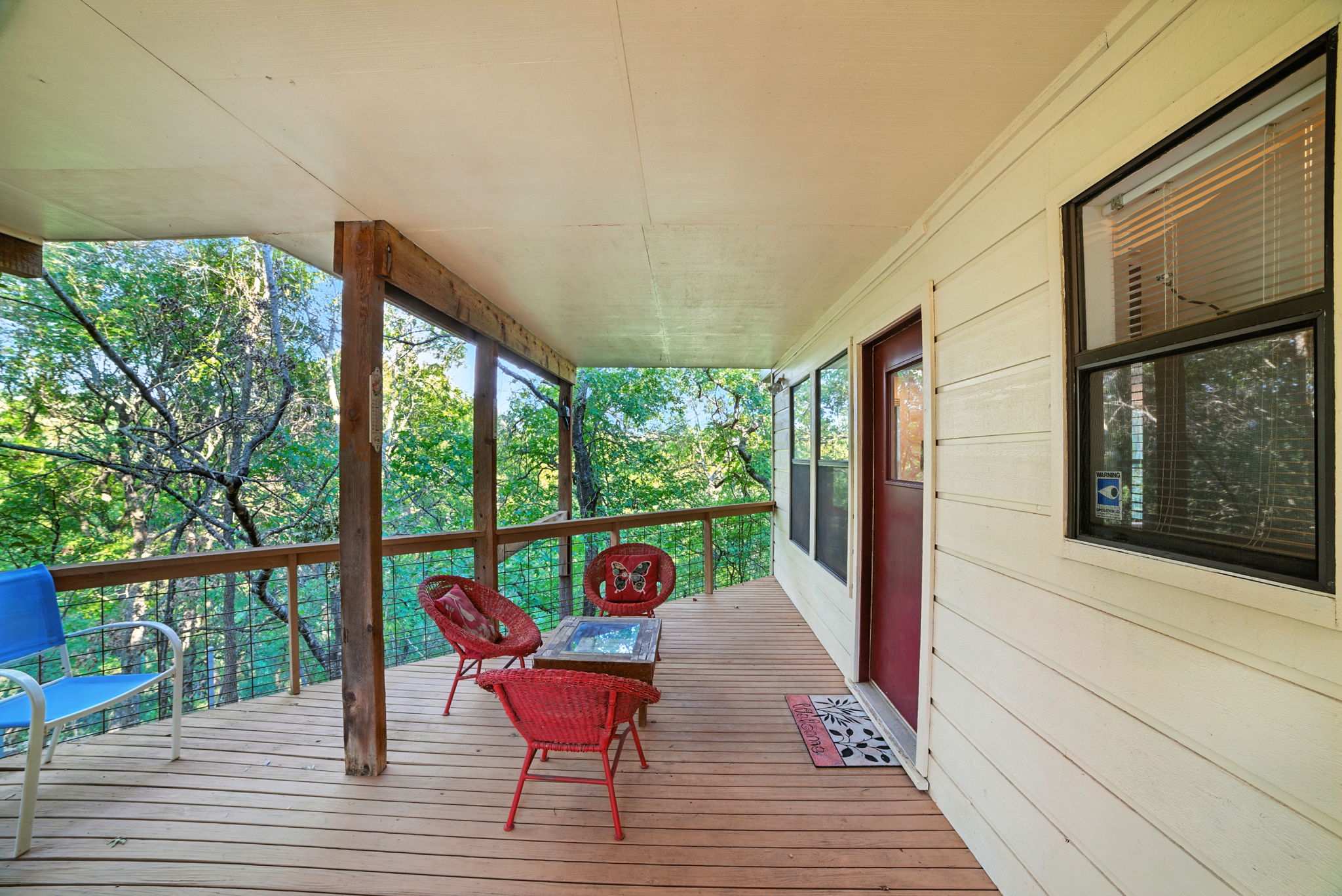 The covered downstairs back patio extends the living space outdoors, offering a shaded retreat with treetop views. From here, you can move easily to the front of the house or into the connected storage area, making it both a relaxing spot and a highly functional hub for daily living.