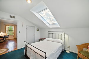 From another angle, the upstairs bedroom highlights its connection to the loft hallway and the abundance of natural light streaming through the skylight. The flexible layout makes this room a comfortable retreat with plenty of potential.