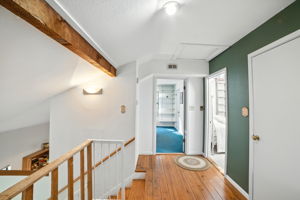 From the loft, the upstairs hallway leads to the home’s bedrooms, with natural light filtering through and wood accents adding warmth. The layout provides privacy between rooms while maintaining an open feel that connects to the rest of the home.