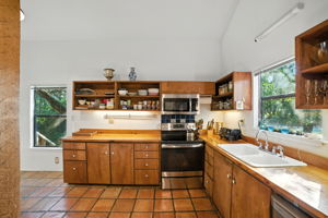 The kitchen is filled with natural light from windows that frame the surrounding greenery, creating a warm and inviting place to cook or gather. With ample counter space, updated appliances, and a functional layout, this space is designed for both everyday meals and entertaining.
