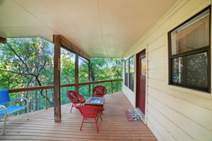 The covered downstairs back patio extends the living space outdoors, offering a shaded retreat with treetop views. From here, you can move easily to the front of the house or into the connected storage area, making it both a relaxing spot and a highly functional hub for daily living.