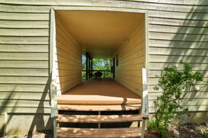 Step through the breezeway, where the home meets a versatile storage area, and follow the path that leads to the back porch and rear entrance. This thoughtful connection enhances the flow of the property, blending function with charm while opening to tree-lined views that highlight the home’s private retreat feel.