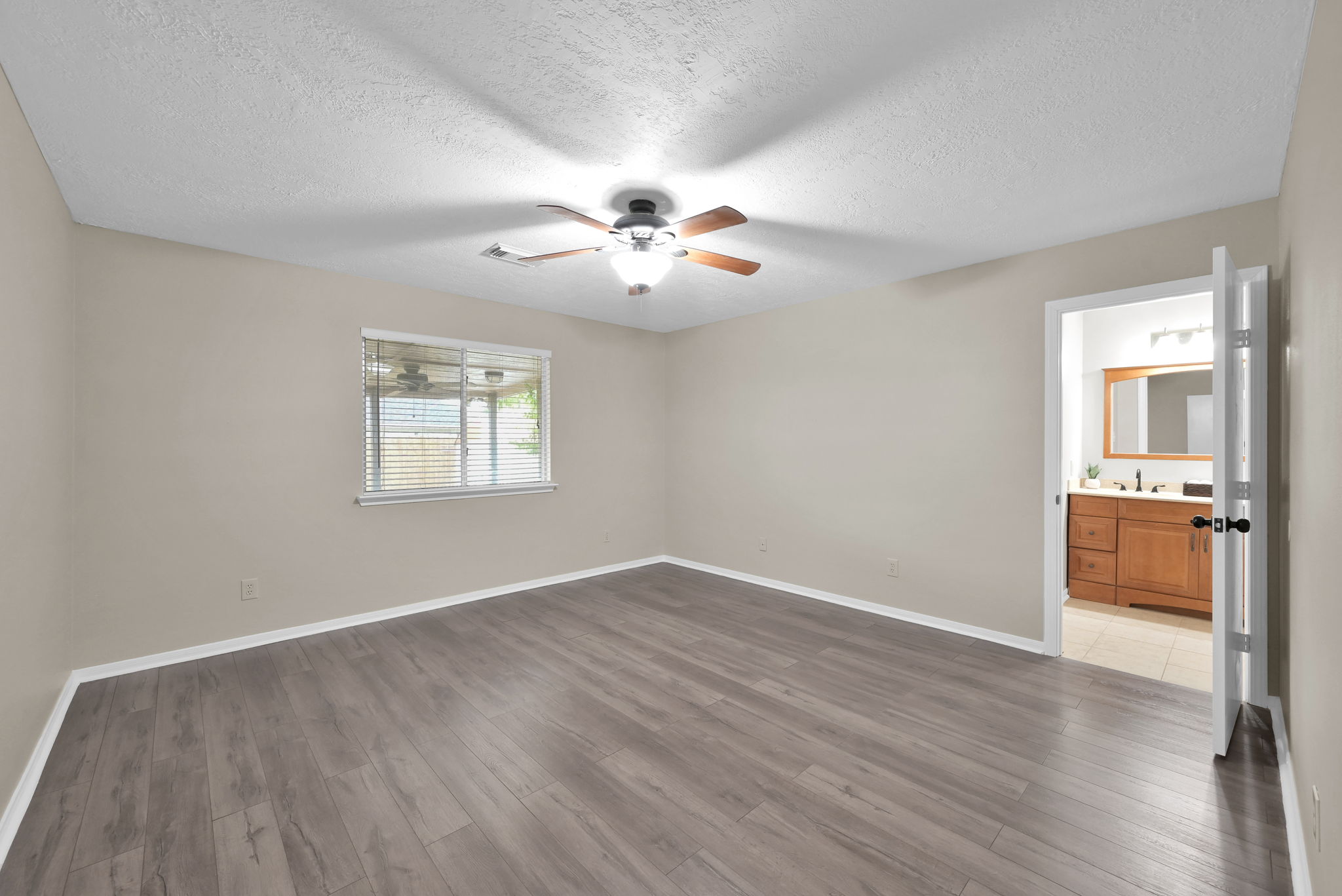 View of the PRIMARY BEDROOM - (All bedrooms and living areas in this home have ceiling fans & 2" faux wood blinds.)