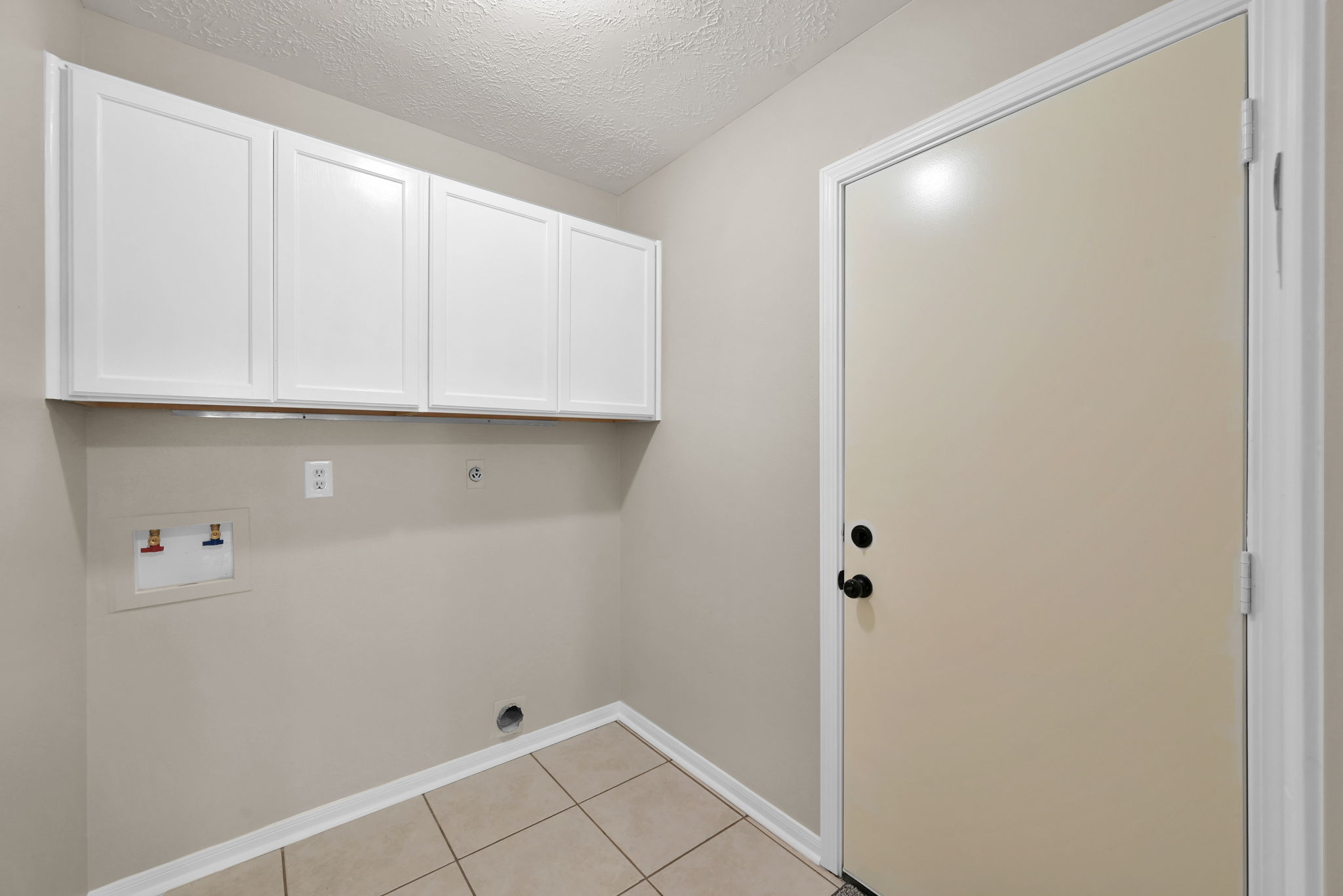 UTILITY ROOM w/ added cabinetry (always nice to have). Door on the right leads to the garage (which has storage cabinets, as well).