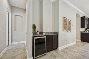 Just off the main living area is a built-in beverage station with granite countertops, custom cabinetry, and a wine refrigerator ...