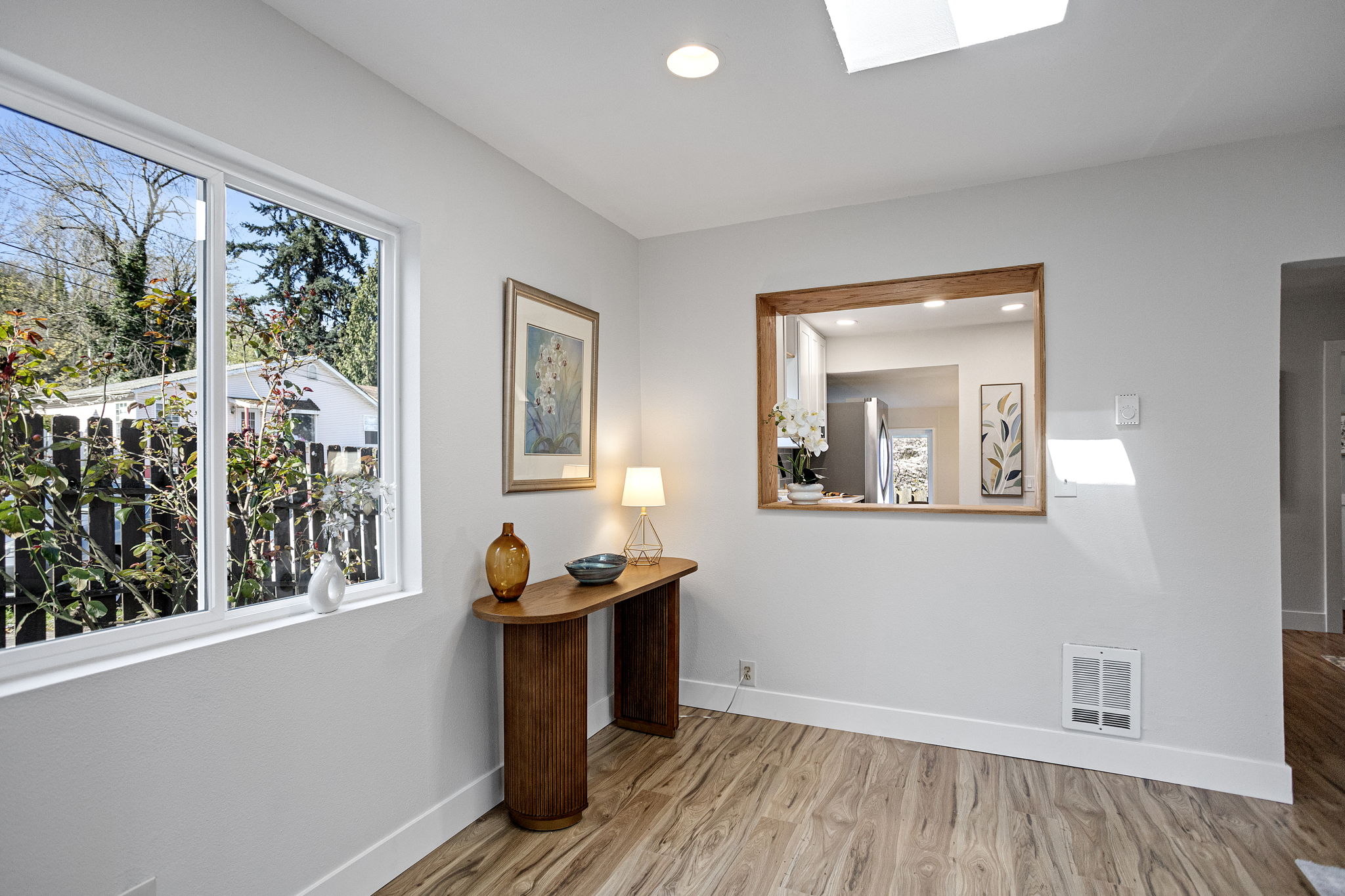 West window to the cobblestone path, wood-framed serve-through to the kitchen — this corner pulls in light and keeps the cook in the conversation.