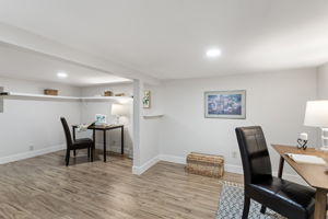 The full picture: two zones, built-in white shelving, LVP flooring. No windows — which makes it a natural media room — but more usable square footage than the bedroom count suggests.