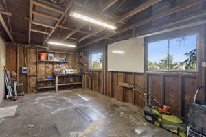Straight from the primary bedroom into a single-car garage with high ceilings, built-in workbench, sub-panel, and two windows. A real workshop.