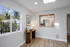 West window to the cobblestone path, wood-framed serve-through to the kitchen — this corner pulls in light and keeps the cook in the conversation.