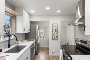 The full run: sink to range, quartz counter to counter — and the spiral staircase in the background is your first hint of what's below.