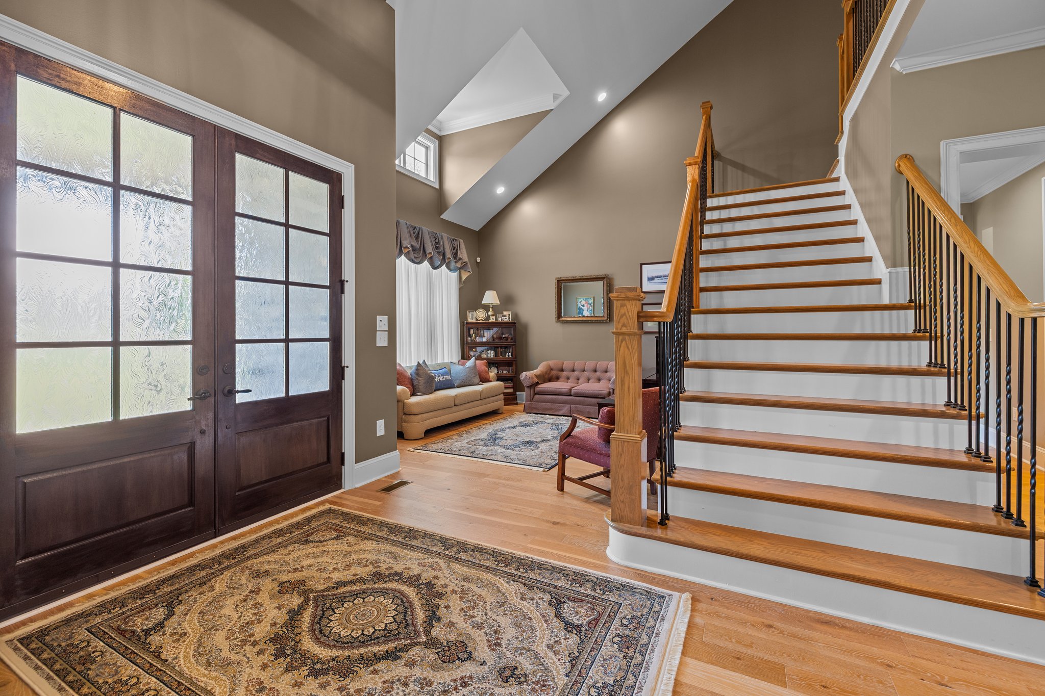 Two Story Foyer with Turn-Style Plank Staircase and Wrought Iron Spindles