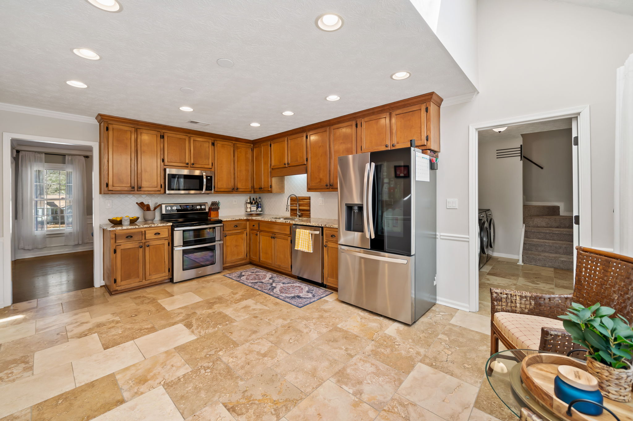 Bright and open eat-in kitchen with travertine tile, stainless appliances and granite countertops.