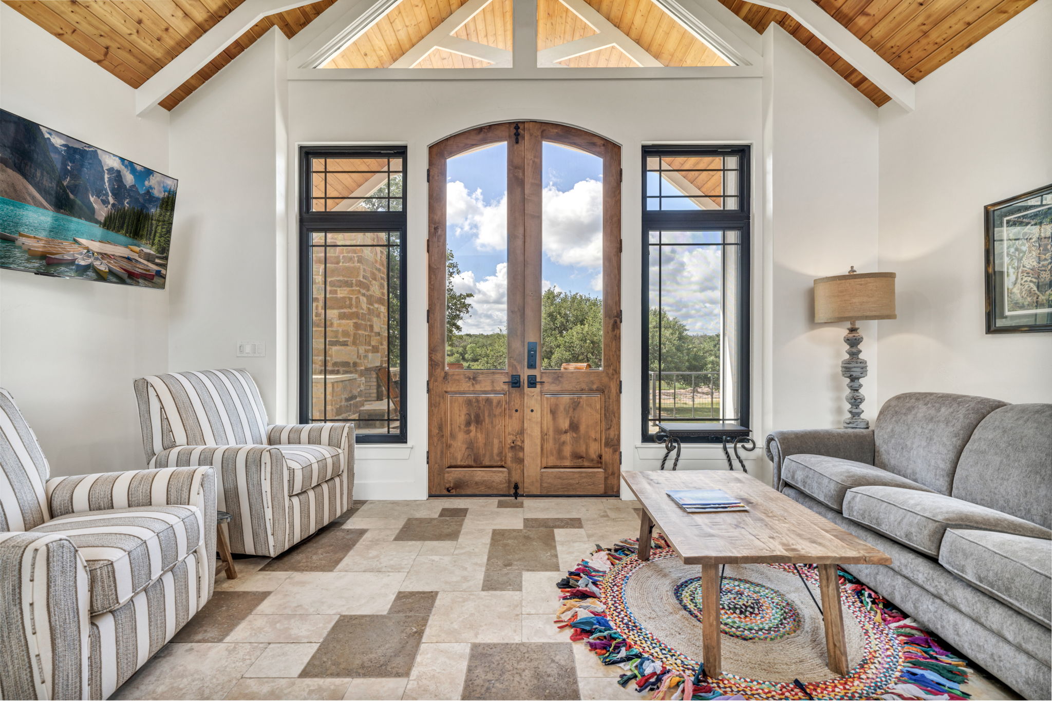 View from kitchen island across living area out to the large patio with rock fireplace