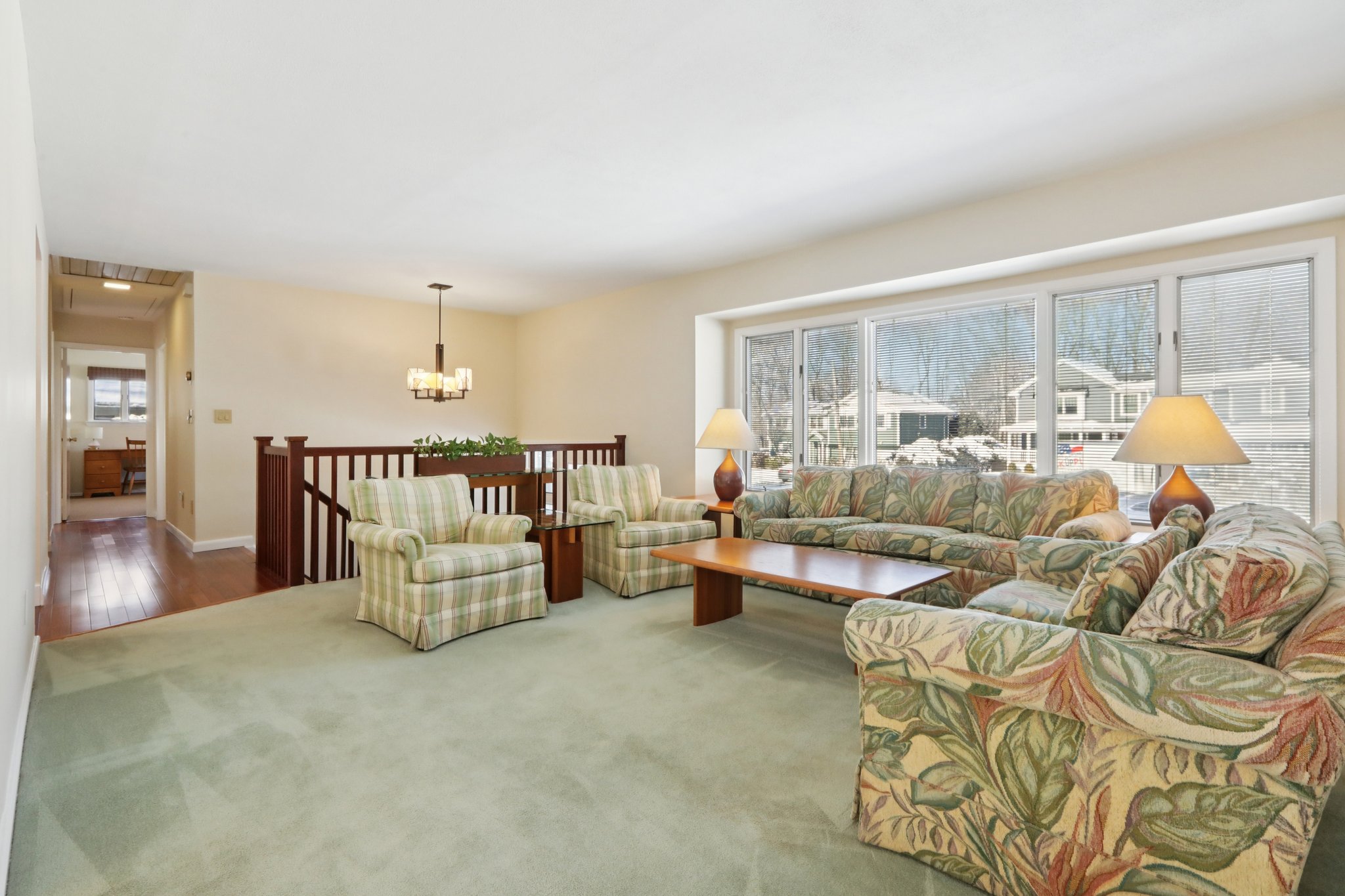 Spacious Living Room with large bay window overlooking the front yard. Notice the railings are carried through to the Living Room. The hallway beyond leads to the bedroom area, with Hall Bath, pull down stairs to attic and attic fan.