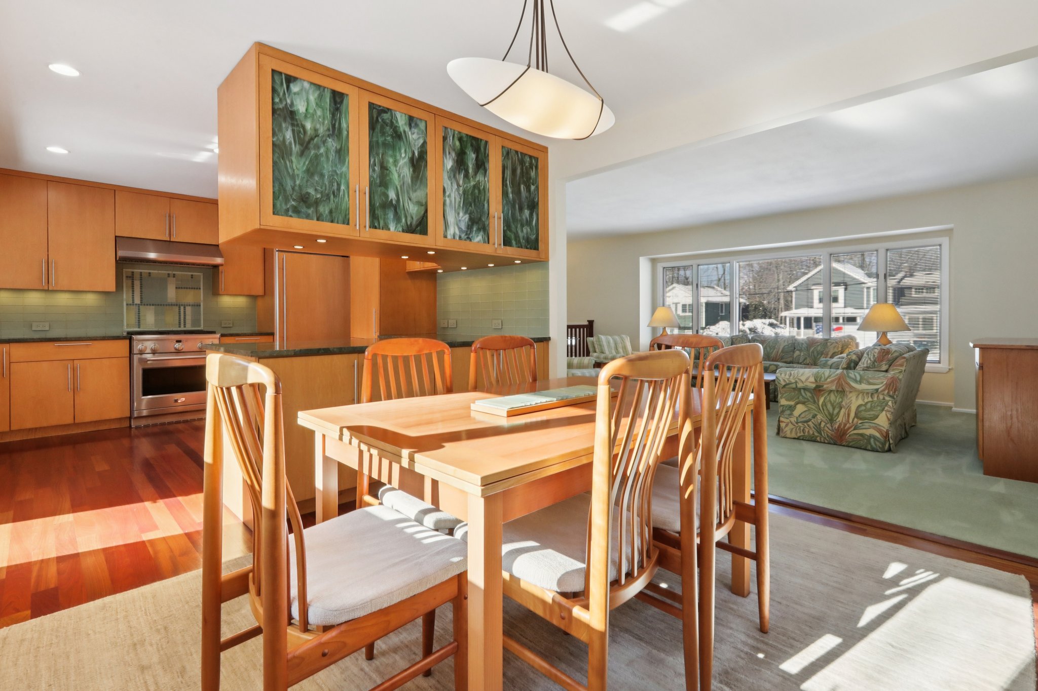 A view of the Dining Area overlooking the Kitchen with art glass (w/lighting behind upper cabinet). Also this view shows the possibility of extending the table for large groups.