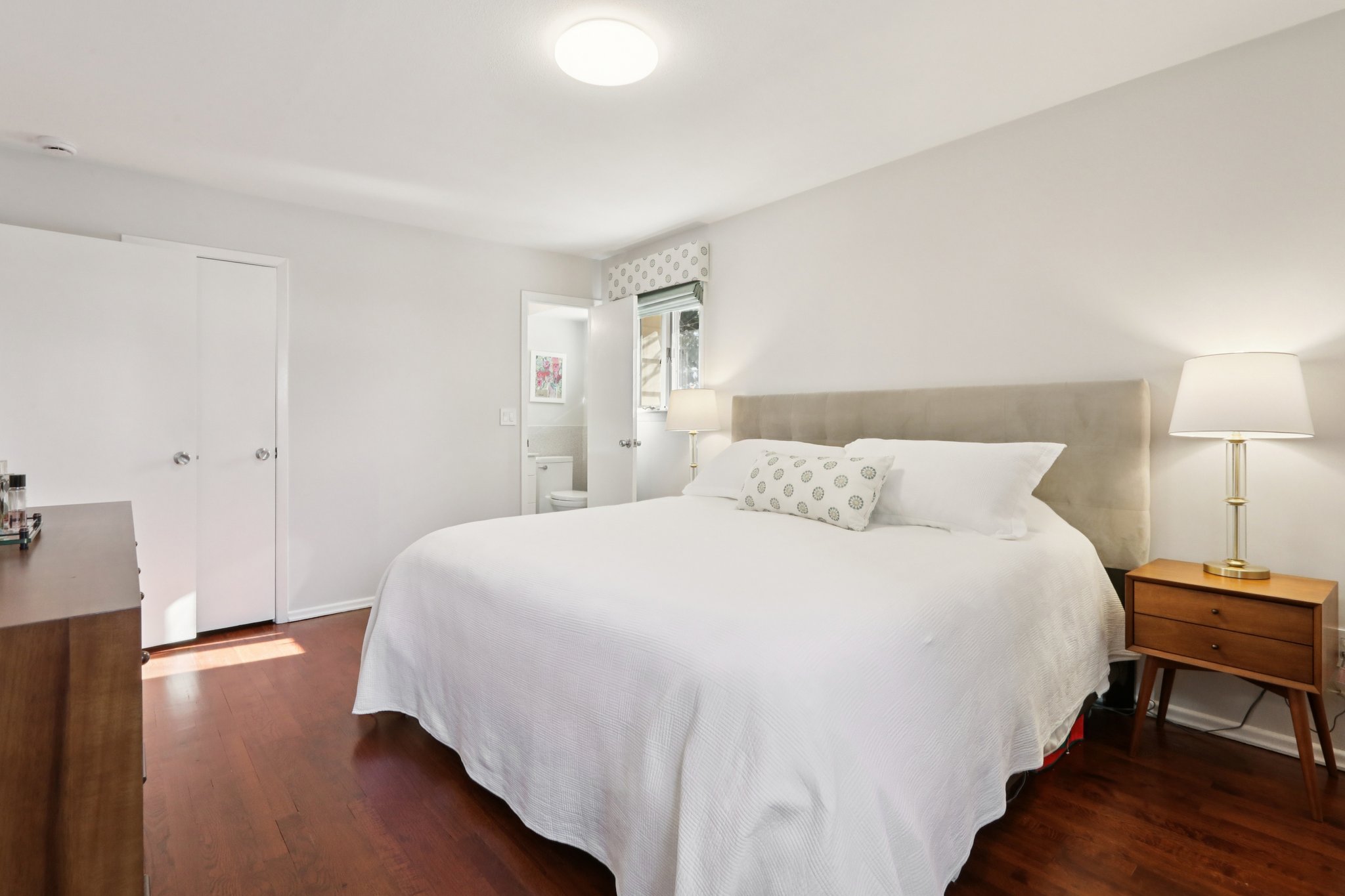 Another view of the Primary Bedroom, with gleaming wood floors, door to closet and door to en-suite bath.