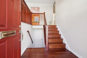 New storm door opens to the newly renovated entry with Brazilian wood railings and complimentary stain on the oak floors.
