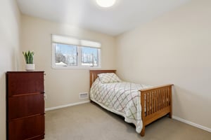 First floor bedroom with a double closet and window facing front yard, carpeted.