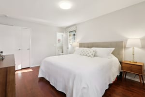 Another view of the Primary Bedroom, with gleaming wood floors, door to closet and door to en-suite bath.