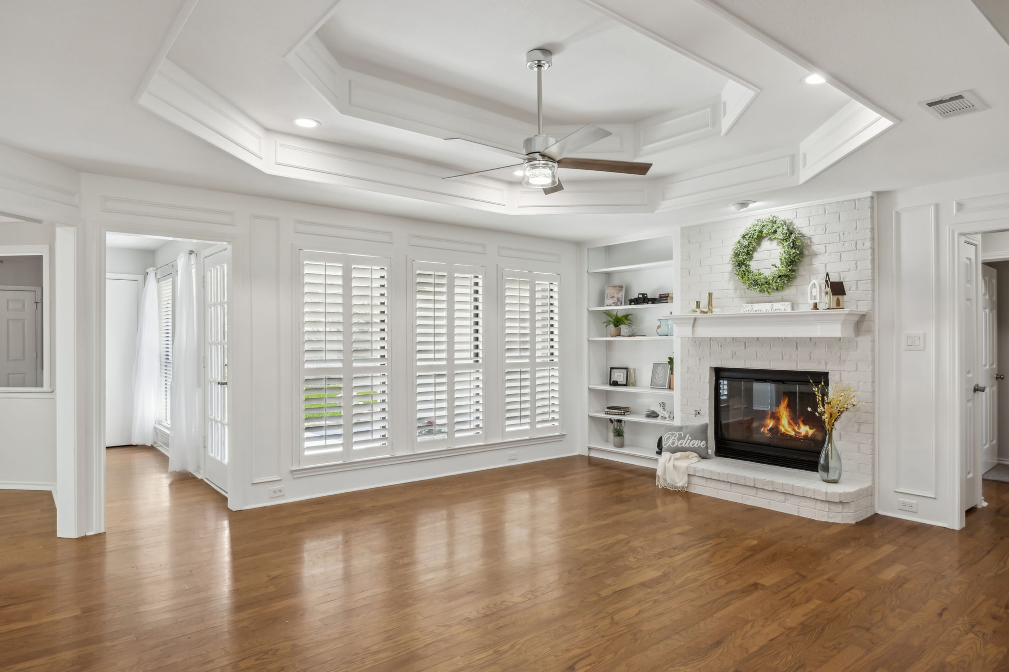 The main living features plantation shutters with views of the  inviting patio and large backyard. Rich and warm wood flooring - cozy fireplace featuring gas logs  - Built in shelves - Tray Ceiling and Upscale NEW Ceiling Fan - The entire home has just been professionally painted inside!