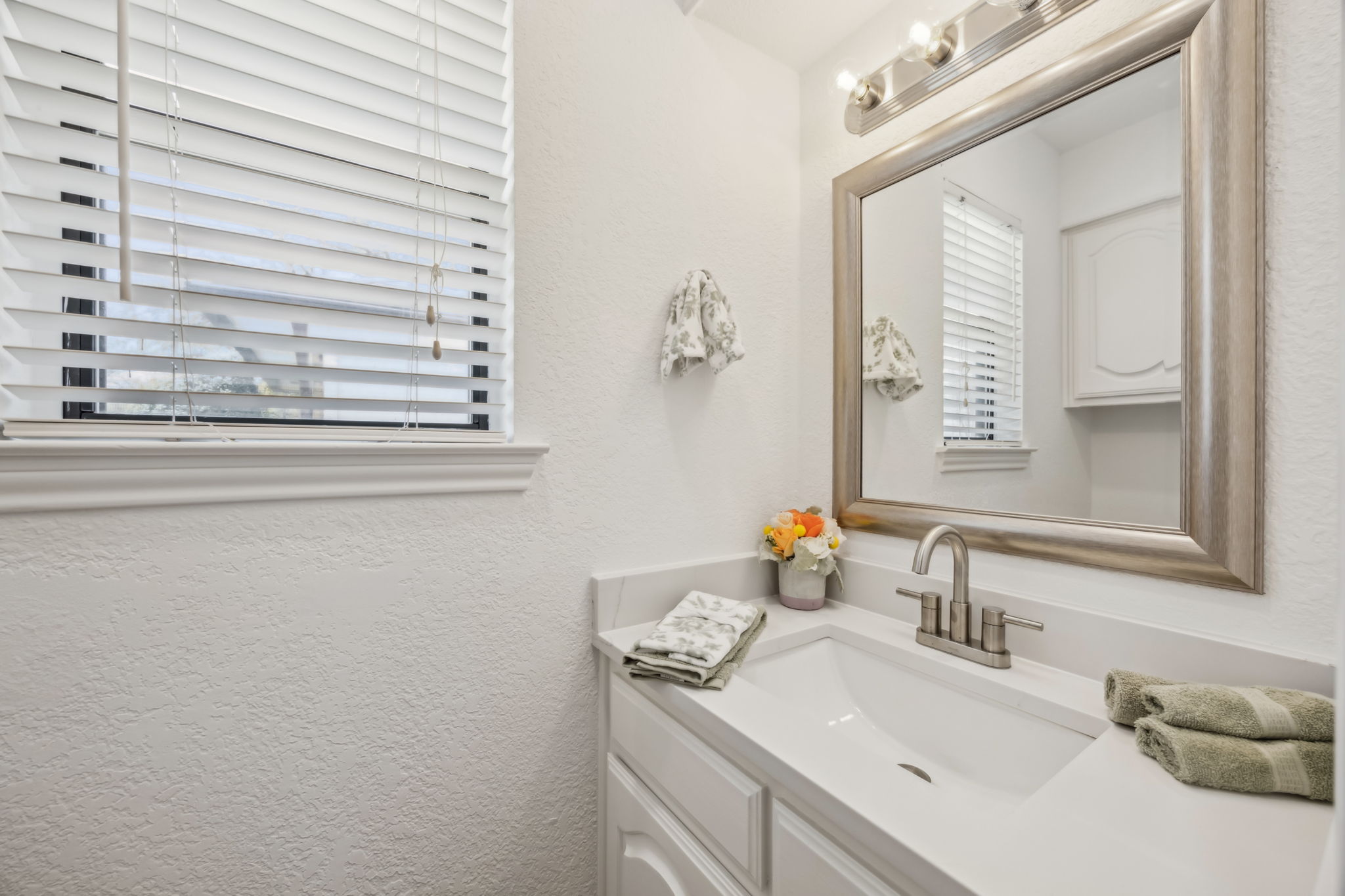 The convenient half-bath has NEW quartz counters, stylish NEW  Faucet, Lighting and Mirror, too!