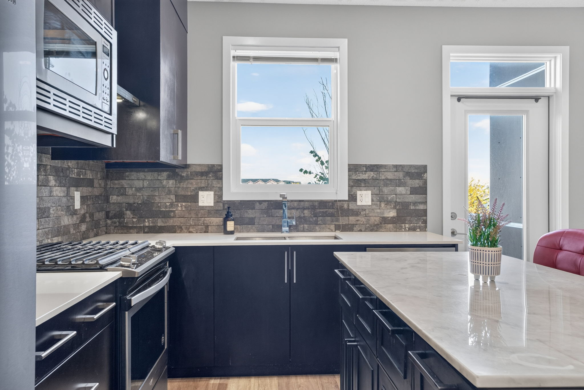 Quartz island, gas range and stone tile to the ceiling