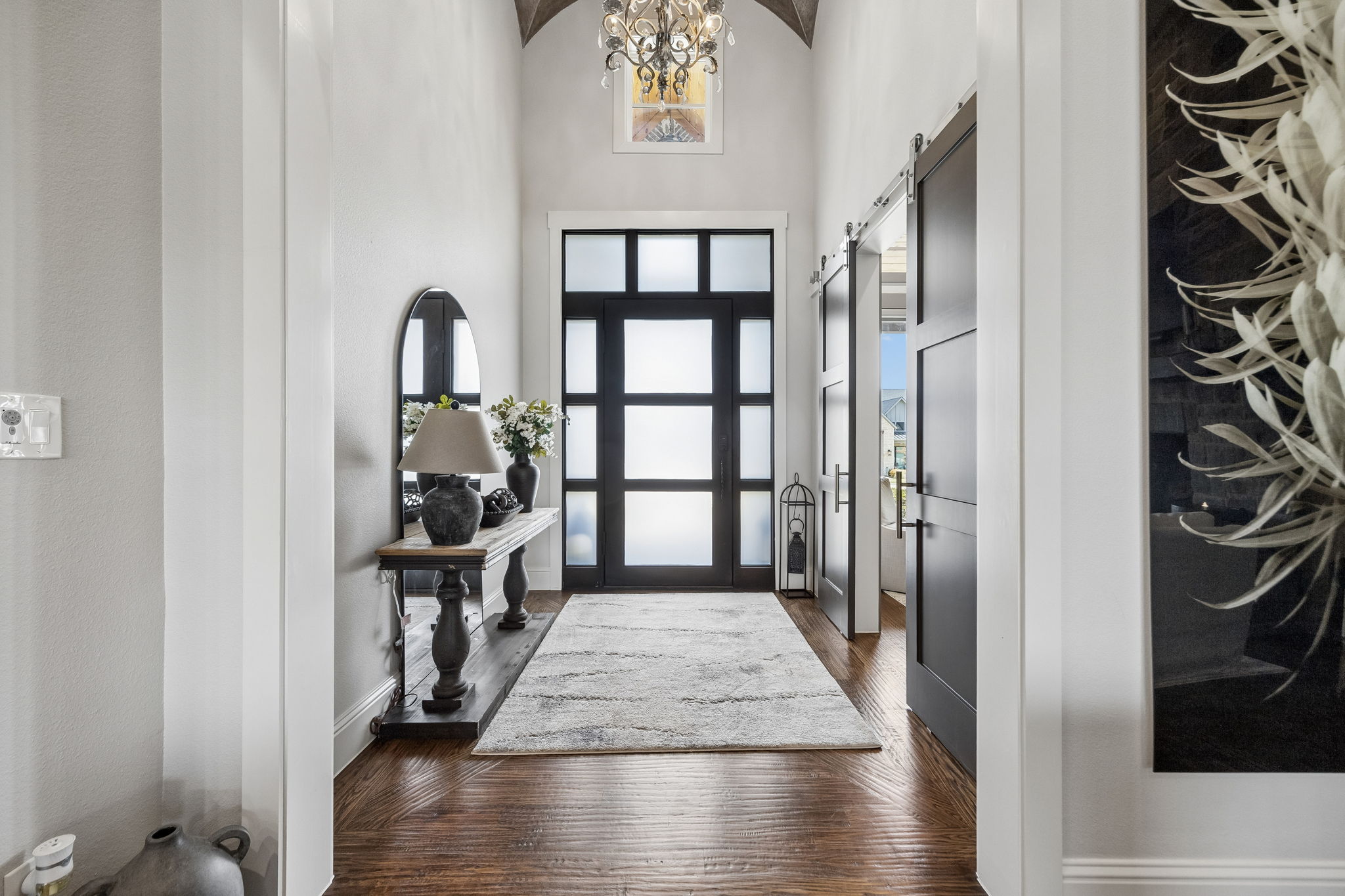 A Dramatic, Light-Filled Entry – A contemporary glass-paneled front door, soaring ceiling, statement lighting, and wide interior openings set the tone for the custom architectural details found throughout the home.