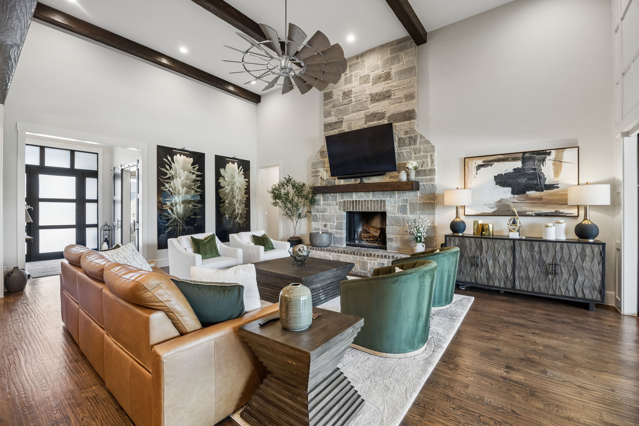 Warm Materials, Impressive Scale – Hand-scraped hardwood floors, a full-height stone fireplace, and dark ceiling beams add warmth and texture to the soaring great room, creating an inviting setting for both everyday living and larger gatherings.