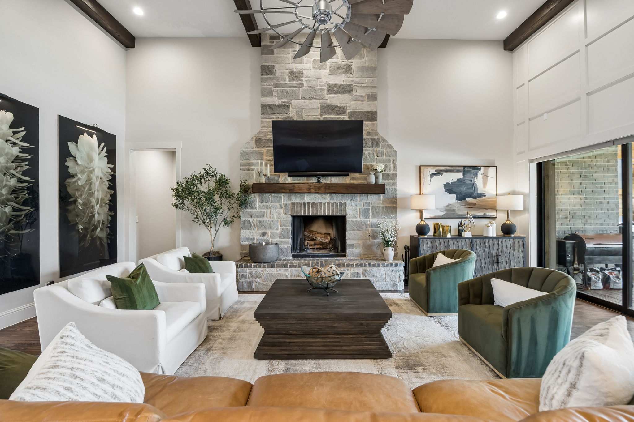 An Inviting Fireplace Focal Point – The full-height stone fireplace, raised hearth, wood mantel, and exposed ceiling beams give the great room a strong architectural centerpiece while maintaining generous space for multiple seating arrangements.