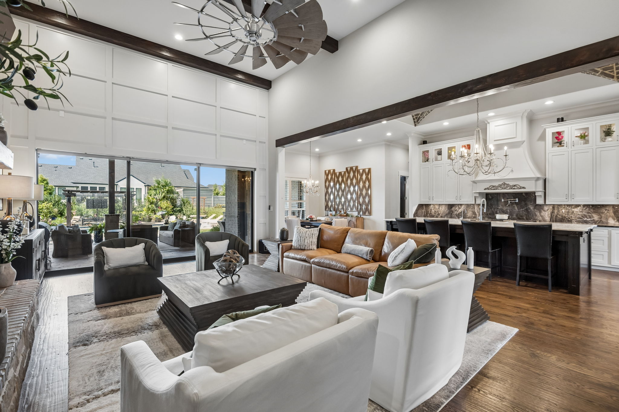 Indoor-Outdoor Living at Its Best – The great room opens directly to the covered terrace through a wide glass wall, creating an easy flow between the kitchen, living area, outdoor seating, and pool.