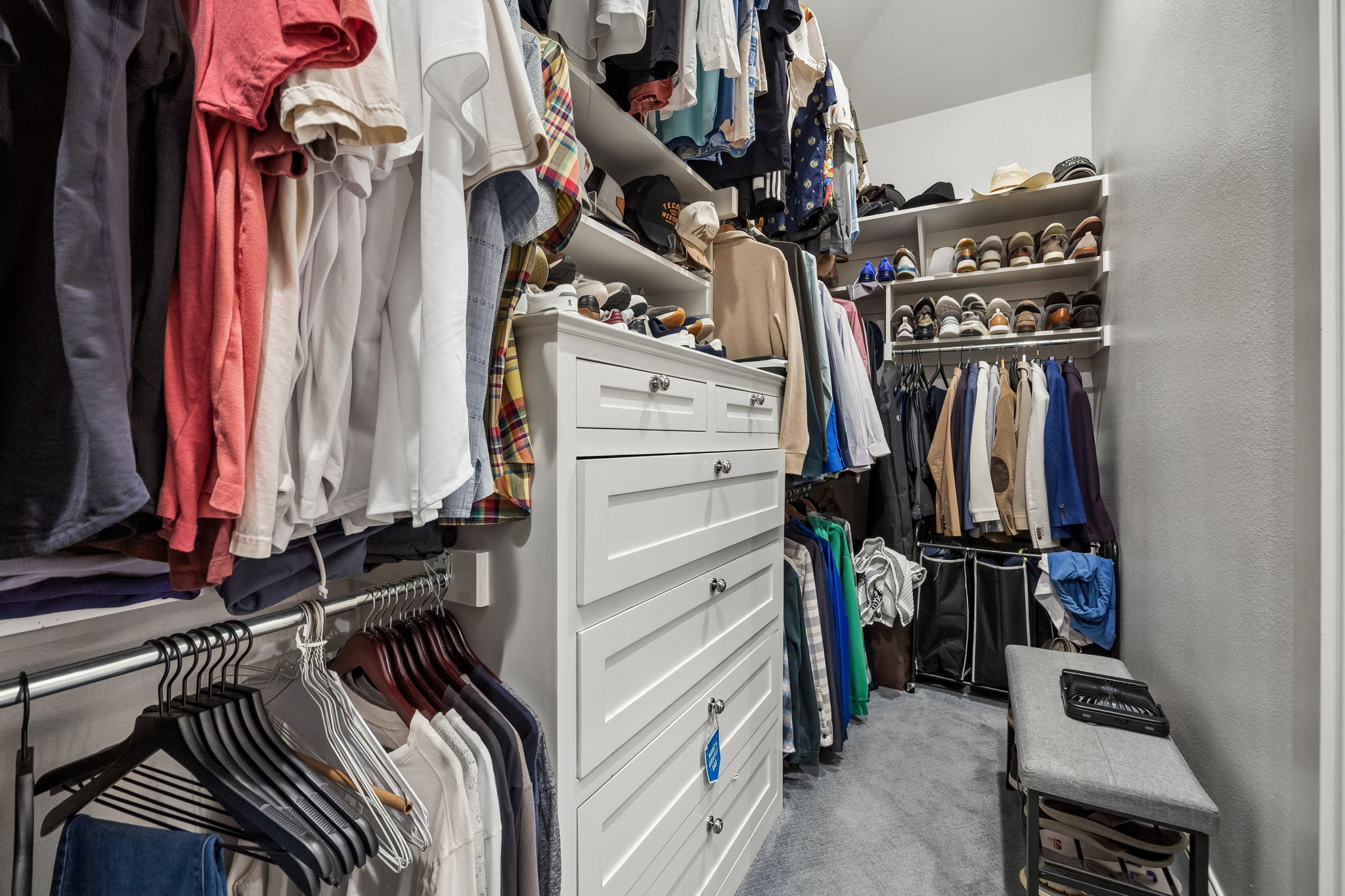 A Walk-In Closet with Built-In Organization – Custom drawers, double hanging areas, open shelving, and dedicated shoe storage make efficient use of the space while keeping everyday essentials easy to access.