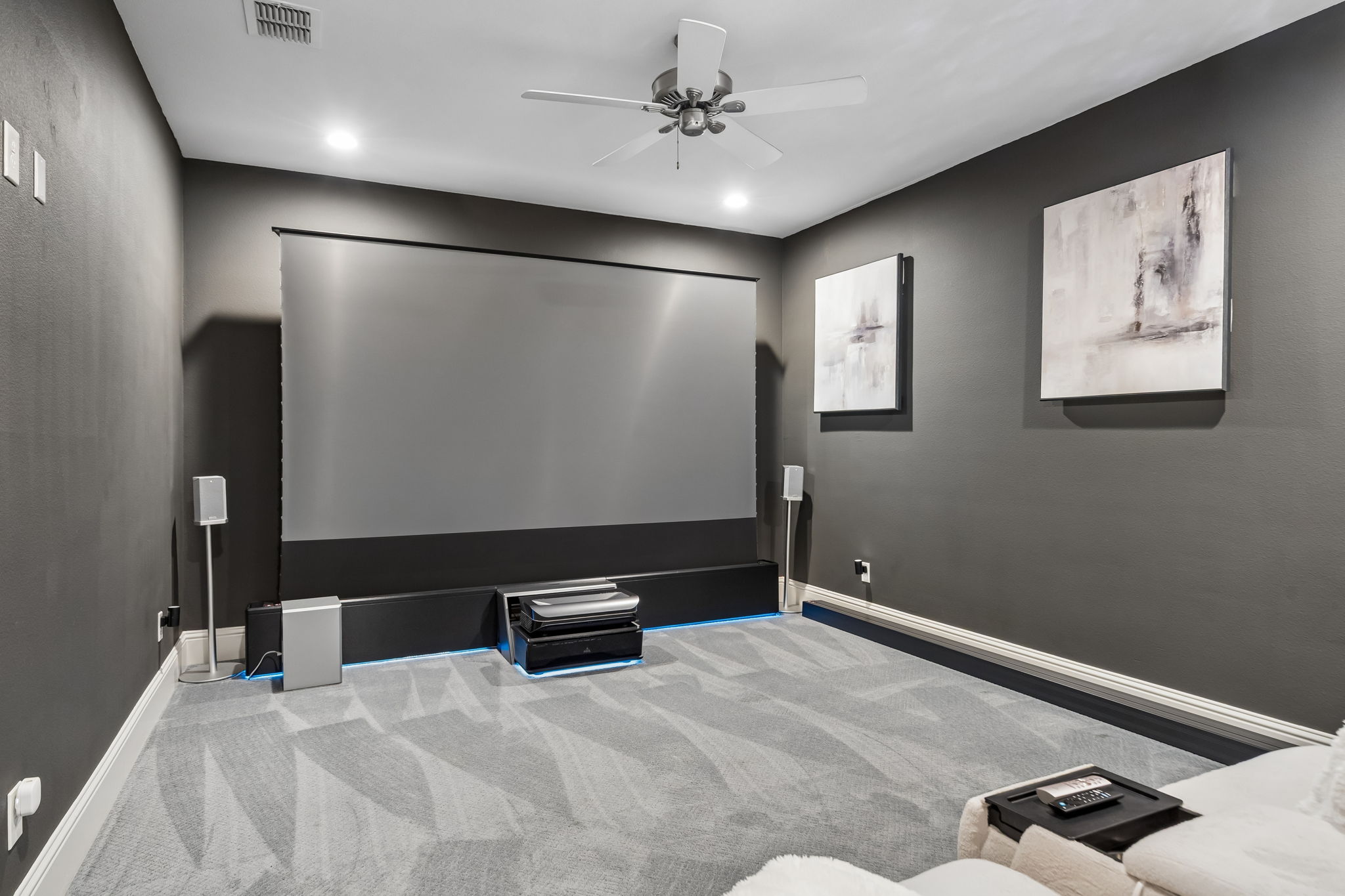 An Entertainment Space with Room to Settle In – The elongated media room provides generous seating distance from the screen, recessed lighting, and space for a refreshment station.