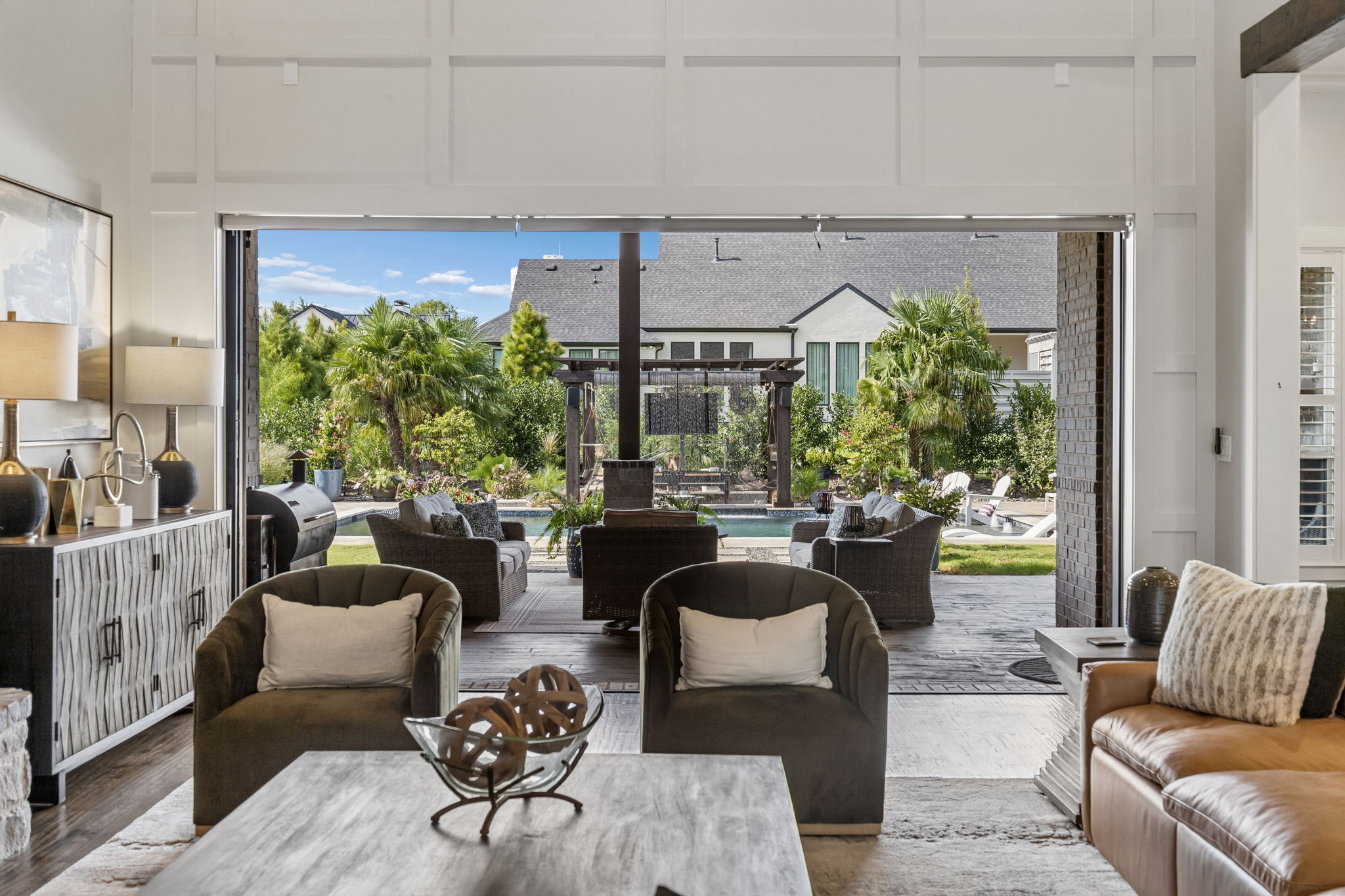 A Seamless View to the Backyard – Fully opened glass panels dissolve the boundary between the great room and covered terrace, creating a direct sightline to the pool, pergola, and landscaped yard.