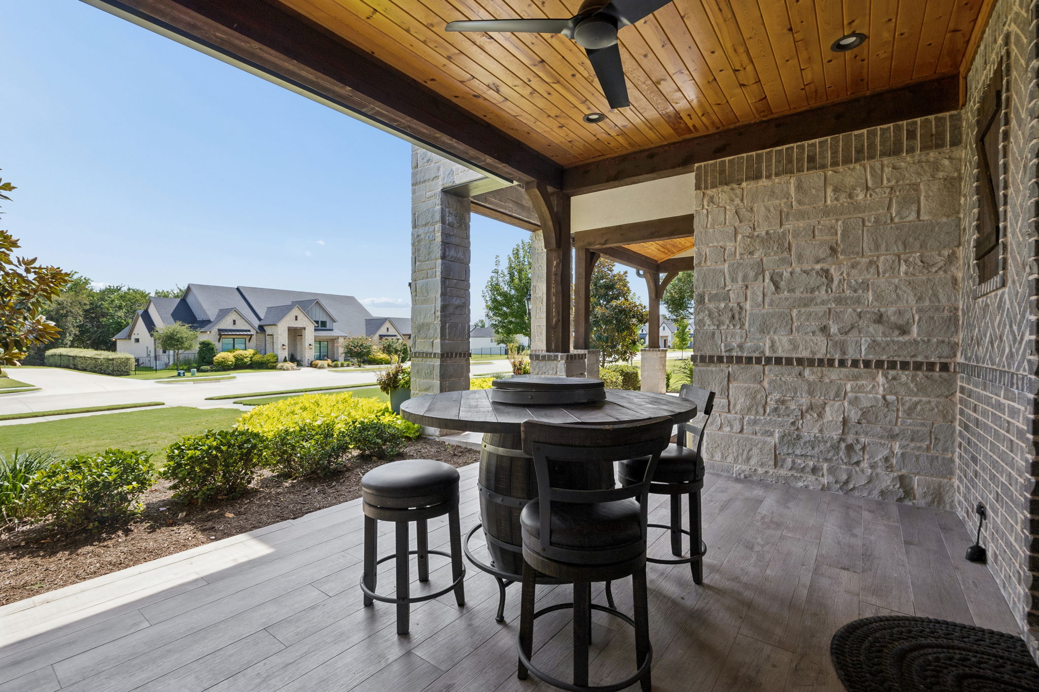 A Welcoming Covered Front Terrace – This sheltered outdoor space extends the home’s living area toward the front lawn, with a cedar ceiling, ceiling fan, stone and brick detailing, and room to relax while enjoying the streetscape.