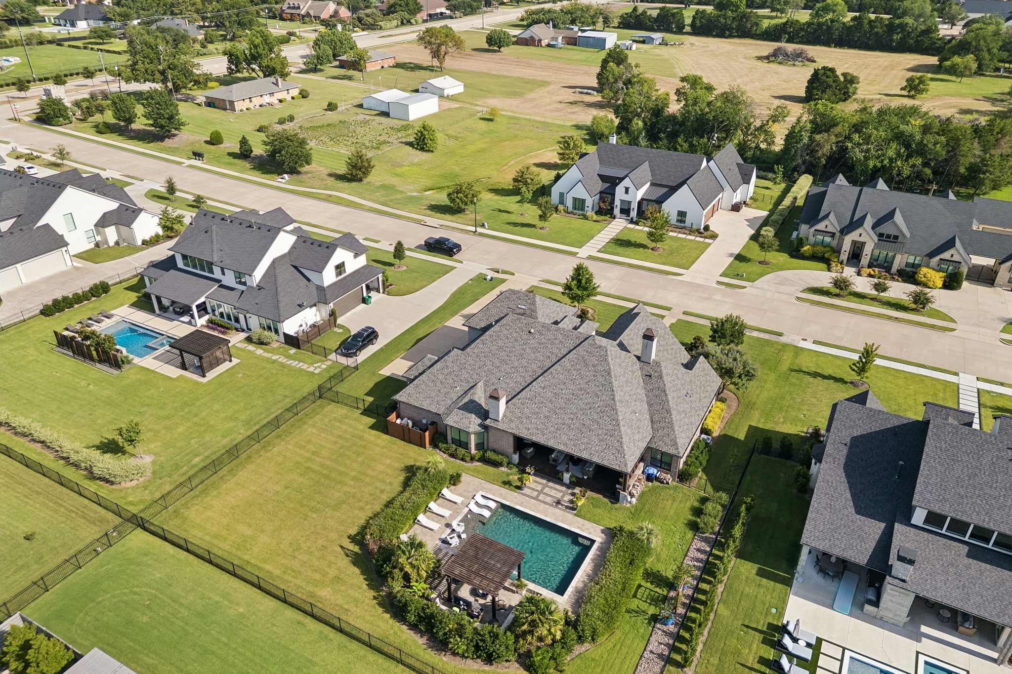 A Well-Placed Backyard Retreat – The pool and pergola sit behind the home with surrounding lawn and landscaping, creating a defined outdoor destination without overwhelming the property.