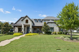 Custom Architecture with Strong Curb Appeal – A striking blend of stone, brick, stucco, metal roofing, and steeply pitched rooflines gives the home a distinctive presence, while the covered entry and mature landscaping create a polished arrival.