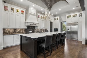 Custom Details Above and Around Every Work Zone – Floor-to-ceiling cabinetry, an architectural vent hood, illuminated stone backsplash, and the hand-laid brick ceiling give this kitchen a level of craftsmanship that stands apart.