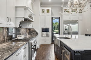 A Professional Kitchen with Purpose – The 48-inch GE Monogram gas range, pot filler, deep farmhouse sink, quartz island, and extensive cabinetry create a highly functional workspace designed for serious cooking and effortless hosting.